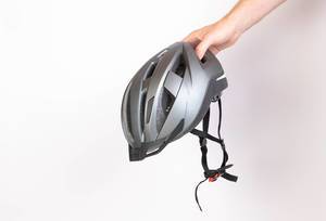 Hand hält einen schwarzen Fahrradhelm für die Sicherheit im Straßenverkehr