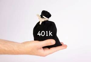 Hand hält einen schwarzen Sack / Geldsäckchen, mit der Aufschrift "401k"