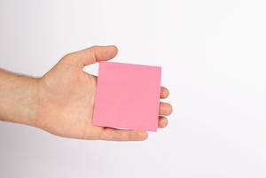 Hand hält leeres, pinkfarbenes Blatt Papier, isoliert vor weißem Hintergrund