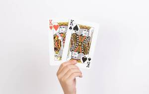 Hand hält zwei Könige-Spielkarten vor weißem Hintergrund