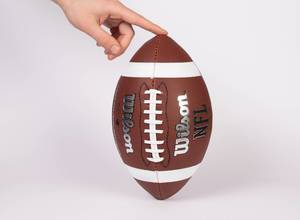 Hand holding a football ready for kicking
