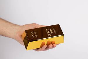 Hand holding a gold bar on white background