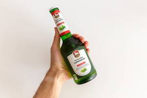 Hand holding a green beer bottle with alcohol-free organic Neumarkter Lammsbräu in front of a white background