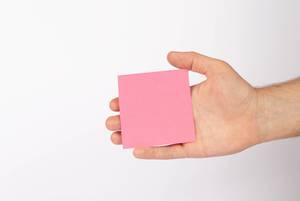 Hand holding empty pink paper isolated on white background (Flip 2019)