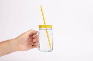 Hand holding glass with drinking straw