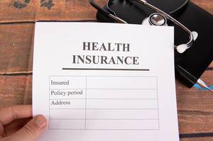 Hand holding health insurance form