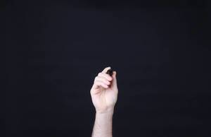 Hand holding pen against black background