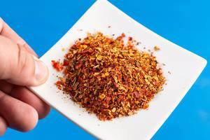 Hand holding plate with Red Grated Chilly Pepper