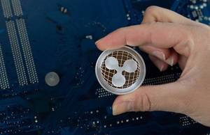 Hand holding silver Ripple XRP coin
