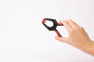 Hand holding small clamp on white background (Flip 2019)