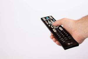 Hand holding tv remote control on white background