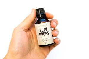 Hand holds aromatic Flav-Drops with coconut flavor by Body attack, for shakes and smoothies