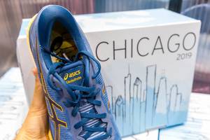 Hand holds blue asics GlideRide running shoes with Chicago marathon 2019 design printed on a shoe box