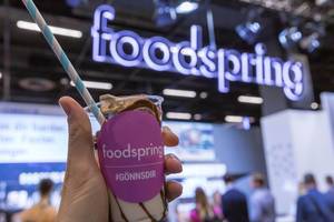 Hand holds foodspring fitness food, healthy snack with chocolate cream at Fibo in Cologne, Germany