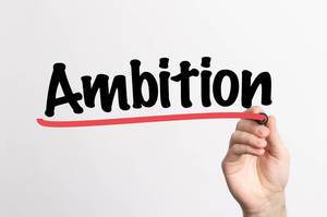 Hand schreibt das Wort "Ambition" auf ein Whiteboard