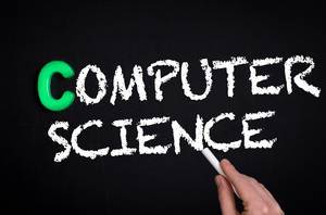 Hand schreibt das Wort "Computer Science" - Computerwissenschaft - mit Kreide auf eine schwarze Tafel