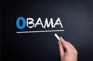 Hand schreibt das Wort "Obama" mit Kreide auf eine schwarze Tafel