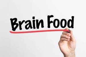 Hand schreibt "Brain Food / Nahrung für das Gehirn" auf ein Whiteboard