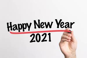 Hand schreibt  "Frohes neues Jahr 2021" auf ein Whiteboard