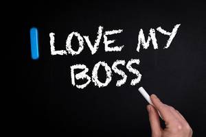 Hand schreibt "I love my Boss" - Ich liebe meinen Chef - mit Kreide auf eine schwarze Tafel