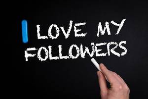 Hand schreibt "I love my Followers" - Ich liebe meine Follower - mit Kreide auf eine schwarze Tafel