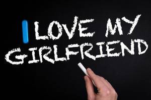 Hand schreibt "I love my girlfriend" - Ich liebe meine Freundin - mit Kreide auf eine schwarze Tafel