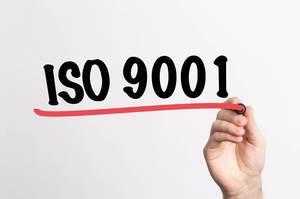 Hand schreibt "ISO 9001" auf ein Whiteboard