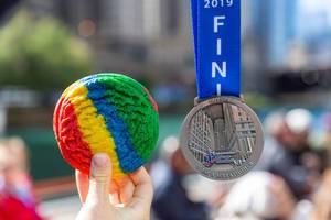 Hand shows a rainbow cookie in a slightly larger size than the Chicago Marathon 2019 finisher medal