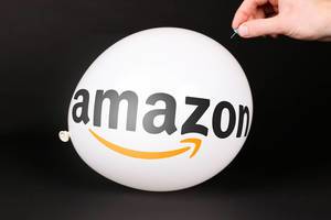 Hand uses a needle to burst a balloon with Amazon logo