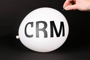 Hand uses a needle to burst a balloon with CRM text