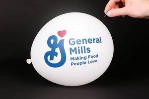 Hand uses a needle to burst a balloon with General Mills logo