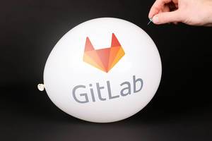 Hand uses a needle to burst a balloon with GitLab logo