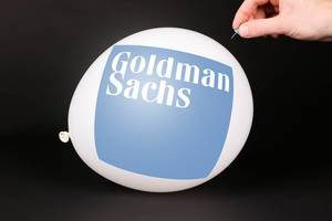 Hand uses a needle to burst a balloon with Goldman Sachs logo