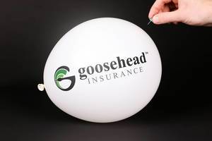 Hand uses a needle to burst a balloon with Gosehead Insurance logo