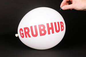 Hand uses a needle to burst a balloon with Grubhub logo