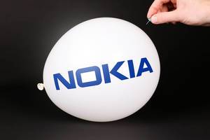 Hand uses a needle to burst a balloon with Nokia logo