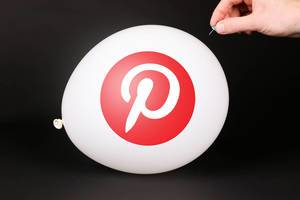 Hand uses a needle to burst a balloon with Pinterest logo