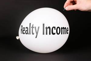 Hand uses a needle to burst a balloon with Realty Income text