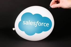 Hand uses a needle to burst a balloon with Salesforce logo
