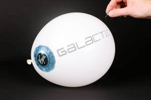 Hand uses a needle to burst a balloon with Virgin Galactic logo