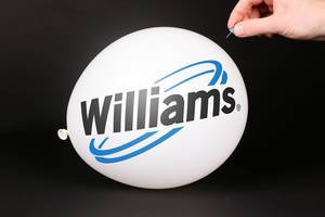 Hand uses a needle to burst a balloon with Williams logo