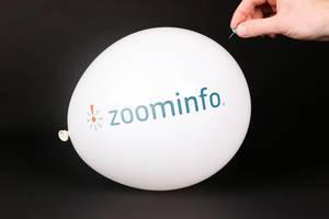 Hand uses a needle to burst a balloon with Zoominfo logo
