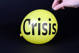 Hand uses a needle to burst a yellow balloon with Crisis text