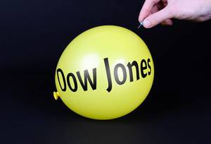 Hand uses a needle to burst a yellow balloon with Dow Jones text