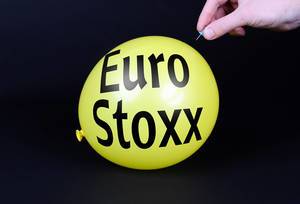 Hand uses a needle to burst a yellow balloon with Euro Stoxx text