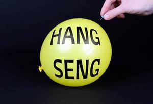 Hand uses a needle to burst a yellow balloon with HANG SENG text