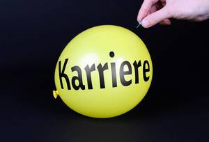 Hand uses a needle to burst a yellow balloon with Karriere text