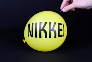 Hand uses a needle to burst a yellow balloon with Nikkei text