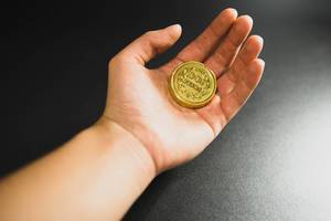 Hand with a two pesos chocolate coin