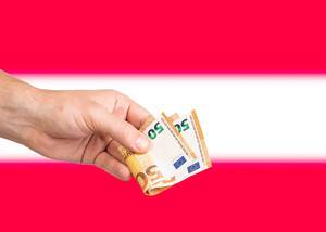 Hand with Euro banknotes over flag of Austria